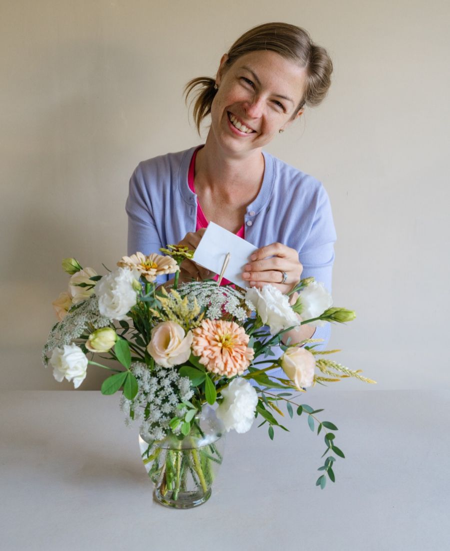 Anna Merkt placing a handwritten note into a vase of light pink flowers